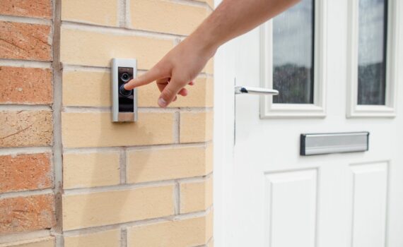 person pushing a doorbell camera